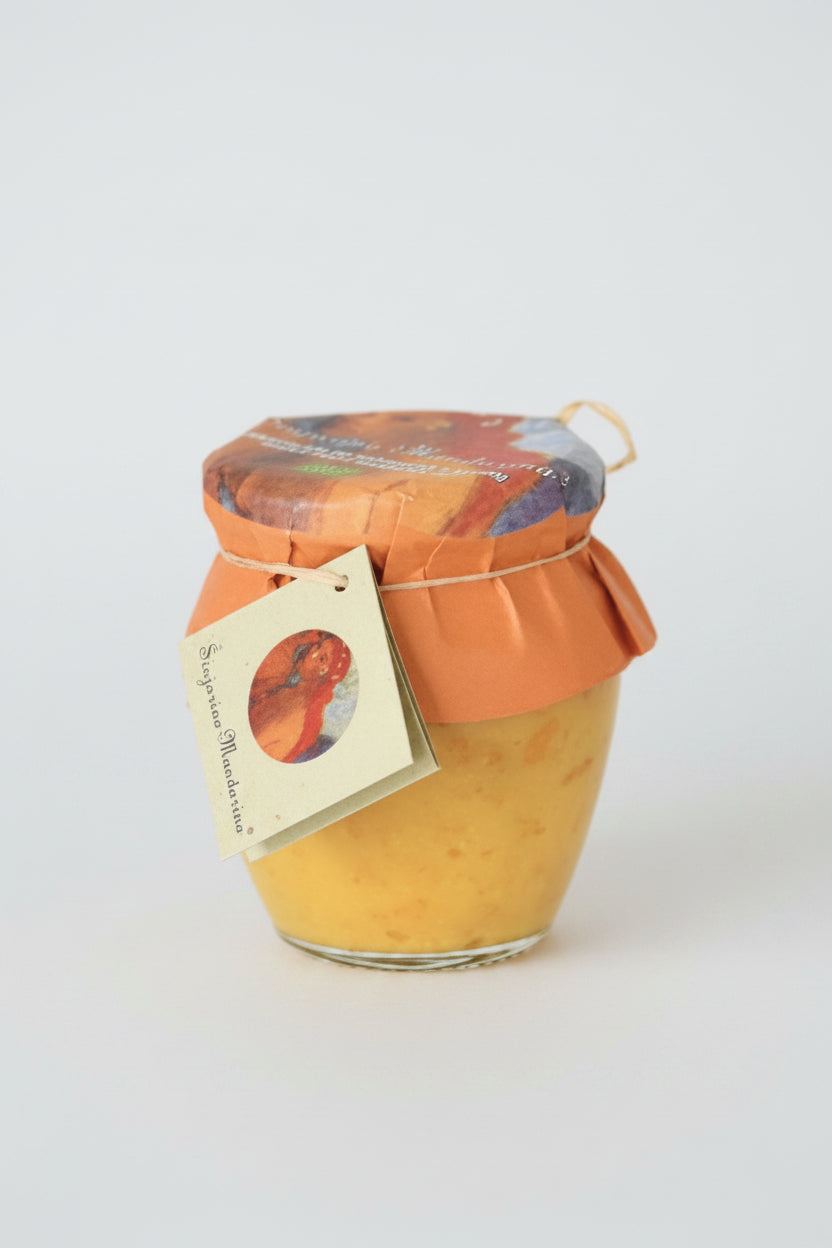 Jar of yellow preserve with an orange lid and decorative label on a white background