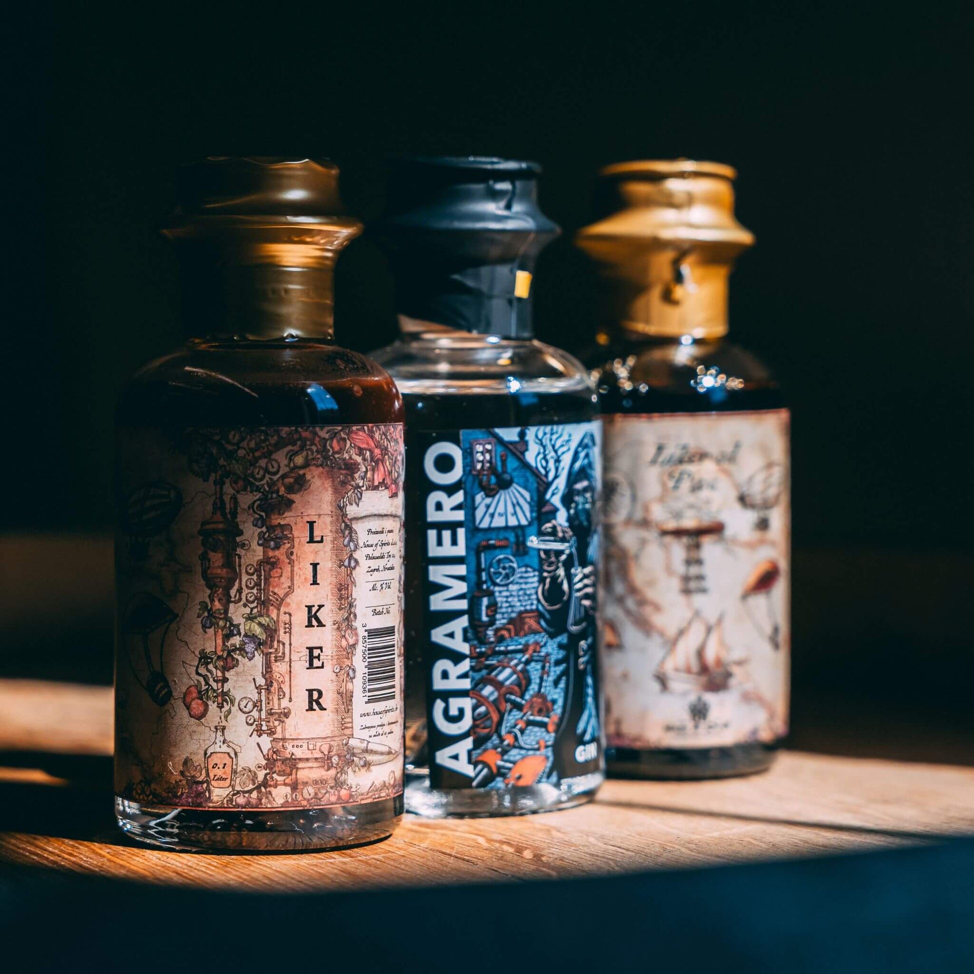 Three bottles of different alcohols on a wooden surface with a dark background